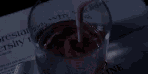 a cherry is being poured into a glass of liquid on top of a piece of paper .