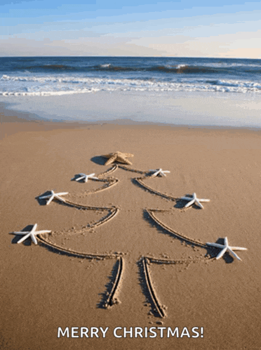 a merry christmas card with a christmas tree drawn in the sand on the beach