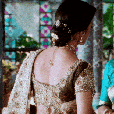 the back of a woman 's blouse has a necklace around her neck