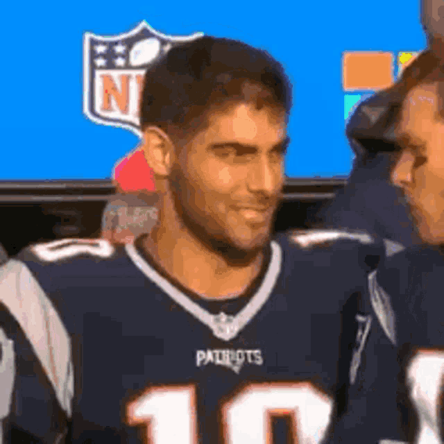 a man wearing a patriots jersey is standing next to another man