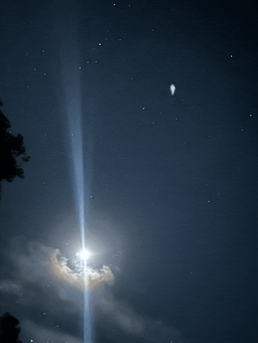 a bright light shines through a cloudy night sky