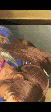 a close up of a woman 's hair with a purple ribbon around her neck