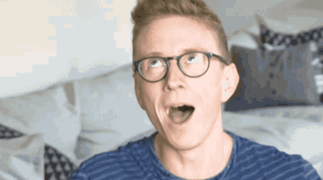a man wearing glasses and a blue shirt is making a surprised face