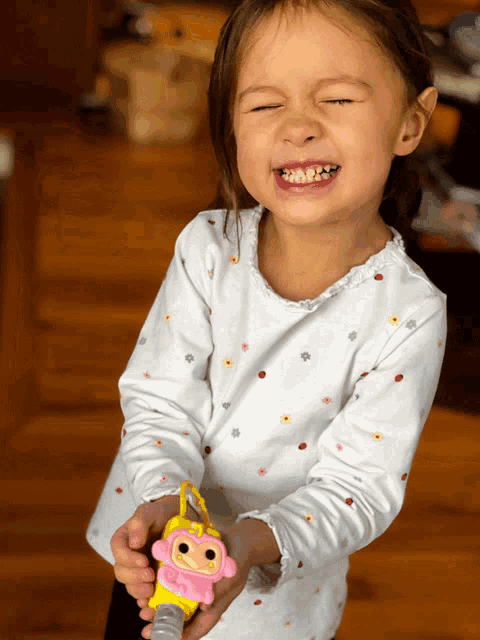 a little girl in a white shirt is holding a toy monkey