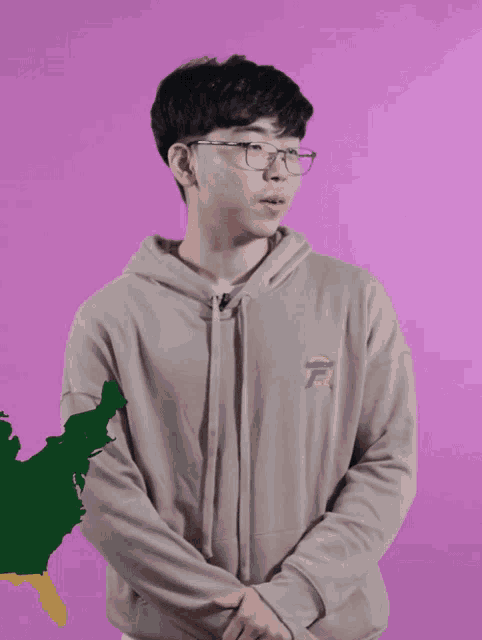 a young man wearing glasses and a tan hoodie with the letter r on the front