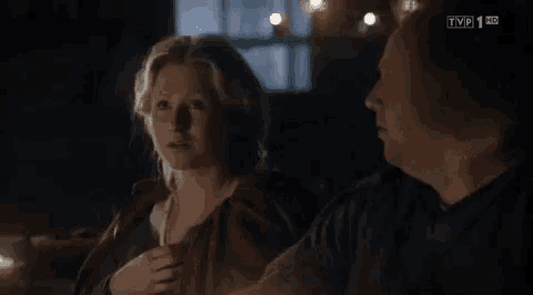 a man and a woman are sitting next to each other in a dark room and talking .