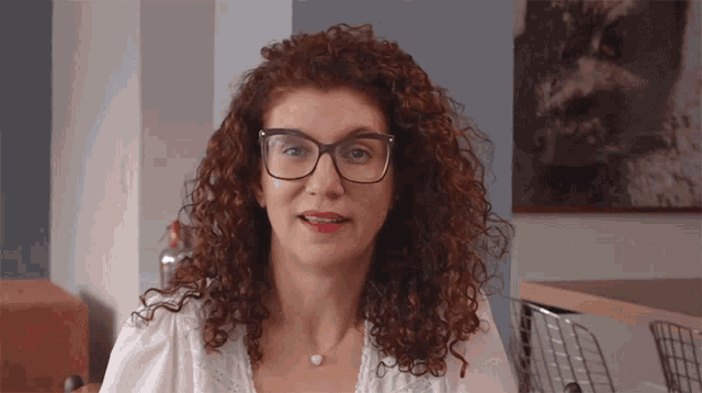 a woman with curly hair and glasses is smiling