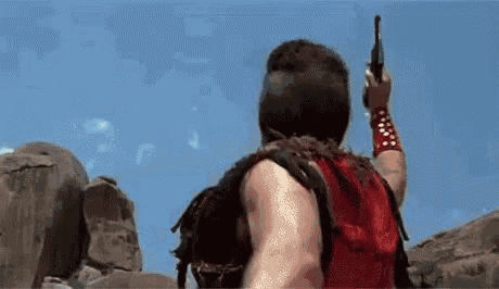 a man in a red shirt is holding a gun in the air .