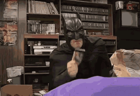 a man in a batman costume is holding a hammer in his hand