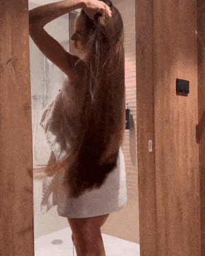 a woman wrapped in a white towel is standing in front of a mirror