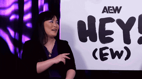 a woman stands in front of a sign that says hey ( ew )