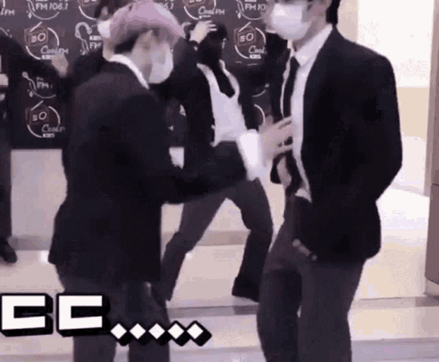 a group of men in suits and masks are dancing in front of a sign that says fm 105.3