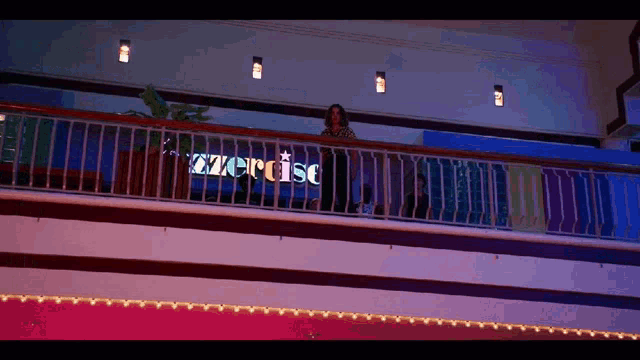 a woman stands on a balcony with a sign that says exercise on it