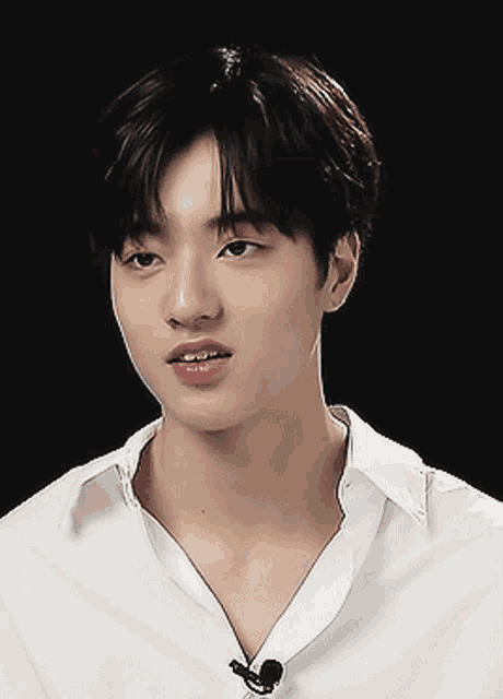 a young man wearing a white shirt with a microphone on his neck