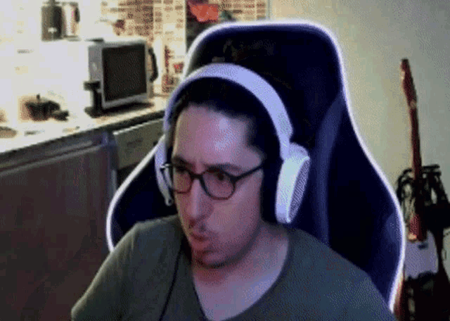 a man wearing headphones and glasses sitting in a chair
