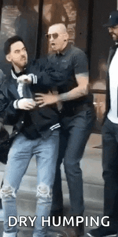 a group of men are standing next to each other and one of them is holding another man 's shirt .