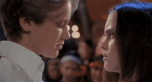 a boy and a girl are looking at each other 's faces .