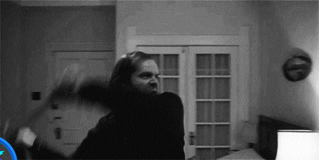 a black and white photo of a man holding another man 's head in a room .