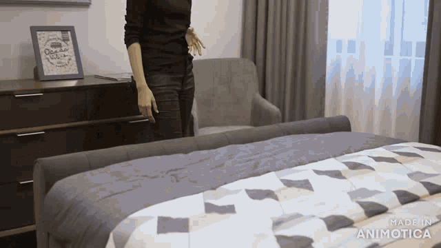 a woman standing next to a bed with a made in animatica logo