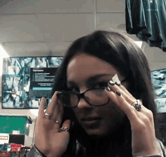 a woman wearing glasses and rings holds her hands to her face