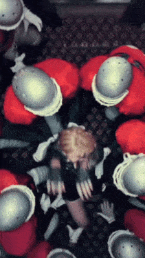 a woman is surrounded by a group of men wearing helmets and gloves