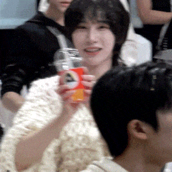 a woman in a white sweater is holding a cup of soda