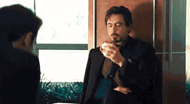 a man in a suit is eating a sandwich in front of another man