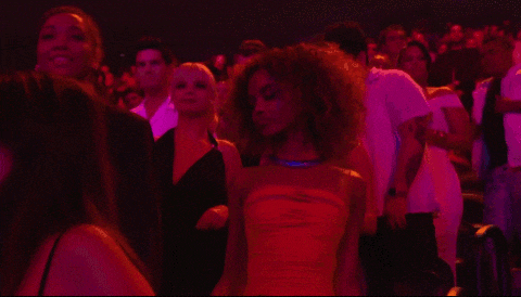a woman in a yellow dress stands in front of a crowd