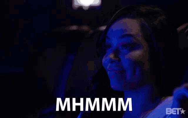 a woman sitting in a dark room with a bet logo on the bottom right