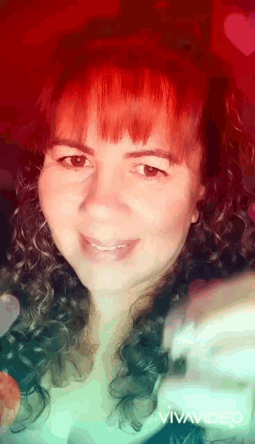 a woman with red hair is smiling in a video .