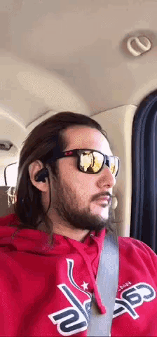 a man with a beard wearing sunglasses and a red hoodie with the word angels on it