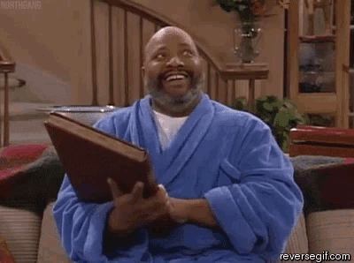a man in a blue robe is reading a book on a couch .