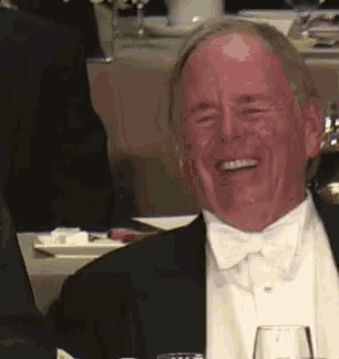 a man wearing a tuxedo and bow tie is laughing