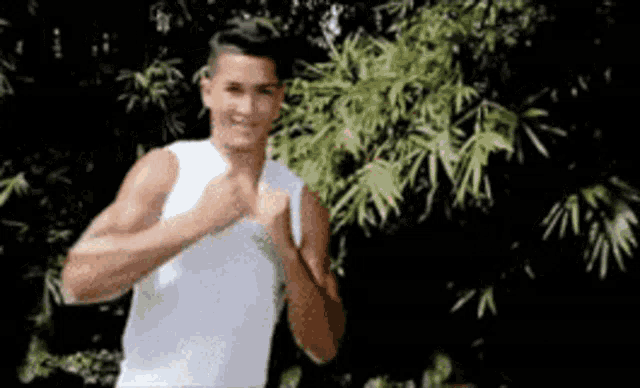 a man in a white tank top is giving a thumbs up .