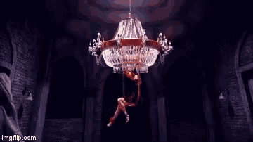 a woman is dancing in front of a chandelier in a room .