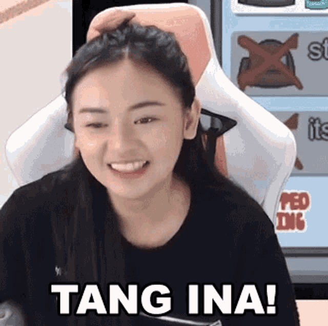 a woman is sitting in a chair with her hand on her head and says tang ina !