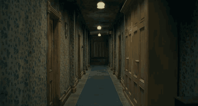 two girls in blue dresses are holding hands in a dark hallway