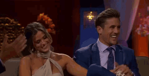 a man and a woman are sitting next to each other on a couch and smiling .