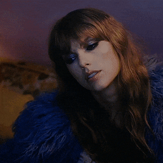 a woman wearing a blue fur coat looks down