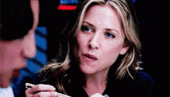 a woman is holding chopsticks and looking at a man while eating .