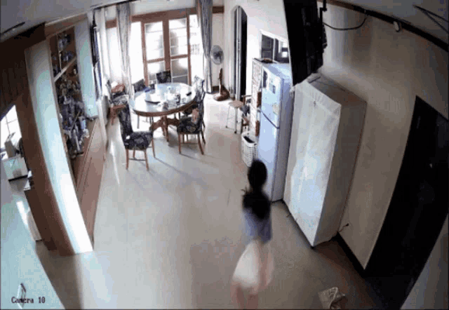 a woman is walking in a room with a camera that says camera 10