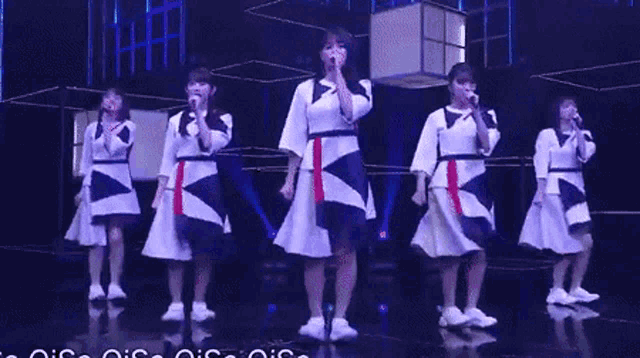 a group of girls are singing into microphones on a stage