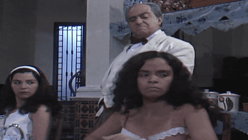 a man in a white suit stands behind a woman in a white top