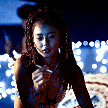 a woman in a bikini smoking a cigarette in a dark room