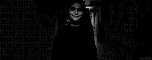 a black and white photo of a little girl with pigtails looking at the camera .