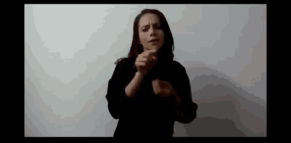 a woman is standing in front of a white wall making a funny face .