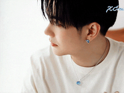 a man wearing a white shirt and a necklace with a blue pendant
