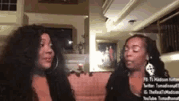 two women are sitting next to each other in a living room .