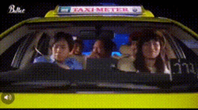a group of people are sitting in a yellow taxi with a taxi meter sign on the top .