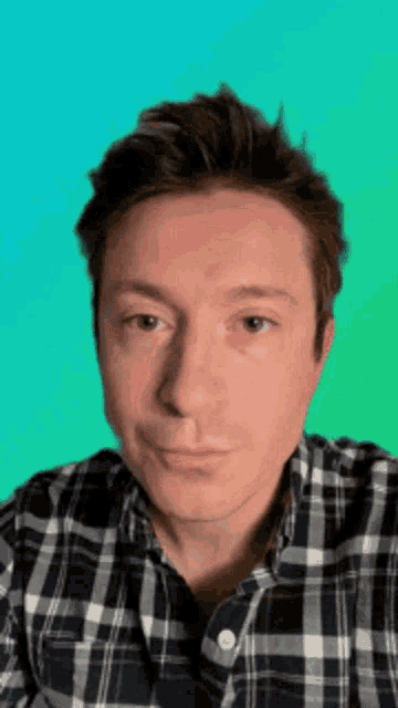 a man wearing a plaid shirt looks at the camera
